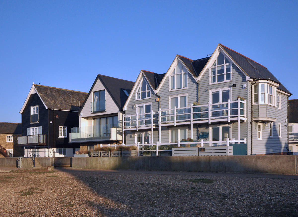 Seafront dwellings on the grounds of the Old Vines public house, standing behind the sea wall, and raised  